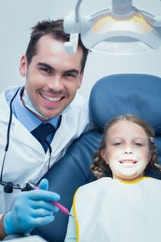 Male dentist examining girls teeth in the dentists chair