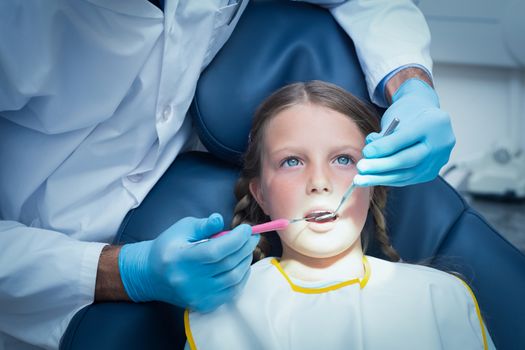 Male dentist examining girls teeth in the dentists chair