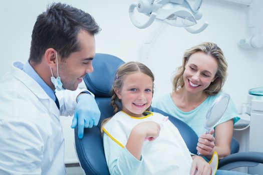 Dentist examining girls teeth in the dentists chair with assistant