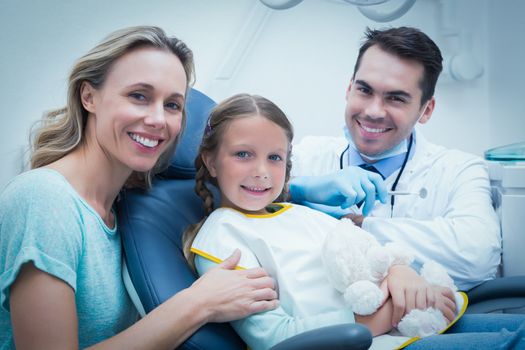 Dentist examining girls teeth in the dentists chair with assistant