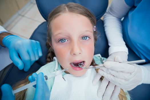 Dentist with assistant examining girls teeth in the dentists chair