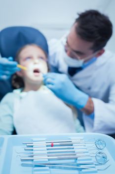 Male dentist examining girls teeth in the dentists chair