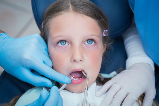 Dentist with assistant examining girls teeth in the dentists chair