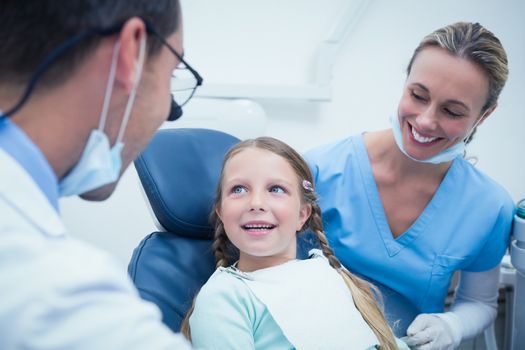 Dentist with assistant examining girls teeth in the dentists chair