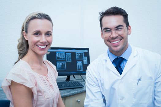 Portrait of smiling male dentist and woman against computer
