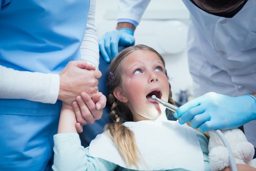 Dentist with assistant examining girls teeth in the dentists chair