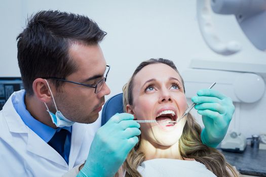 Dentist examining young womans teeth in the dentists chair