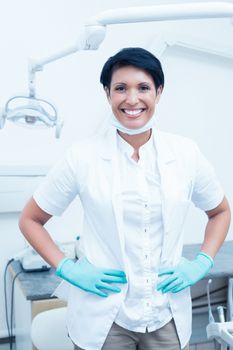 Portrait of happy confident female dentist with hands on hips