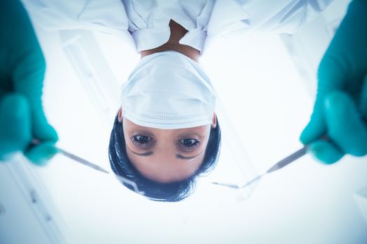 Portrait of female dentist in surgical mask holding dental tools