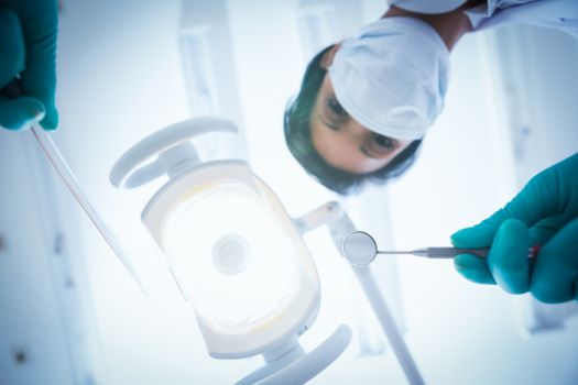 Portrait of female dentist in surgical mask holding dental tools