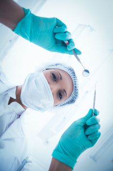 Portrait of female dentist in surgical mask holding dental tools