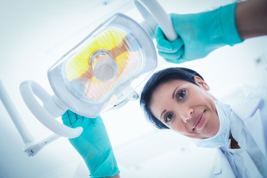 Low angle portrait of female dentist adjusting light