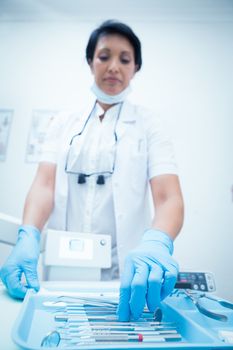 Portrait of female dentist picking dental tools