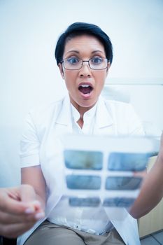 Shocked female dentist looking at x-ray