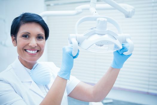 Portrait of smiling female dentist adjusting light