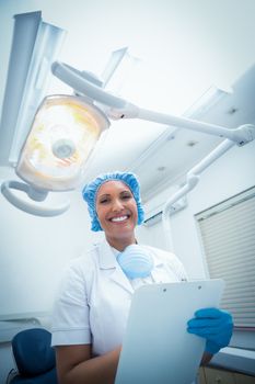 Portrait of smiling female dentist holding clipboard
