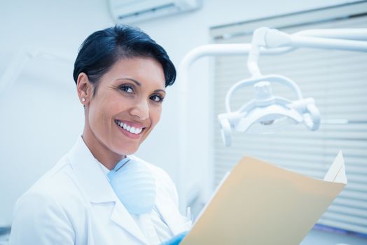 Portrait of smiling female dentist reading reports