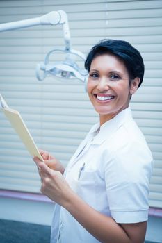 Portrait of smiling female dentist reading reports