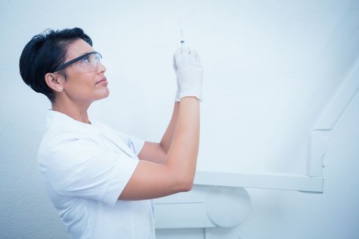 Side view of female dentist holding injection