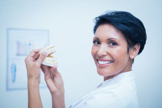 Close up portrait of smiling female dentist holding mouth model
