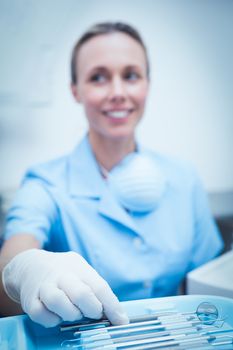 Portrait of female dentist picking dental tools