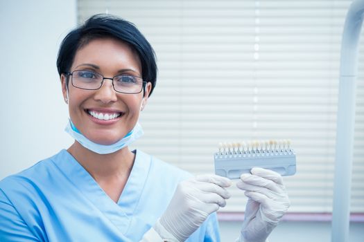 Portrait of smiling female dentist holding teeth model
