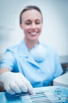 Portrait of female dentist picking dental tools