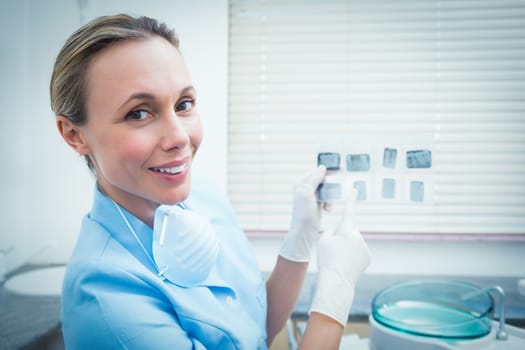 Side view portrait of smiling female dentist holding x-ray