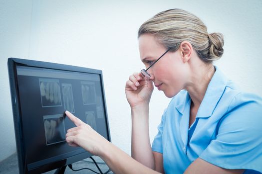 Concentrated female dentist looking at x-ray on computer