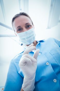 Low angle portrait of female dentist in surgical mask holding injection