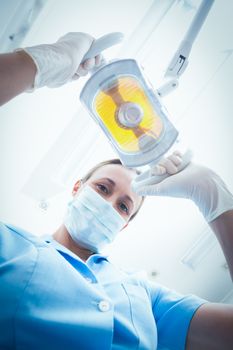 Low angle portrait of female dentist adjusting light