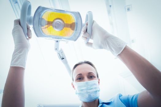 Low angle portrait of female dentist adjusting light
