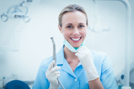 Portrait of smiling young female dentist holding dental tool