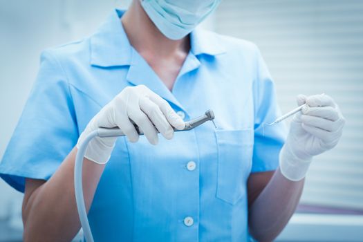 Close up mid section of female dentist holding dental tools