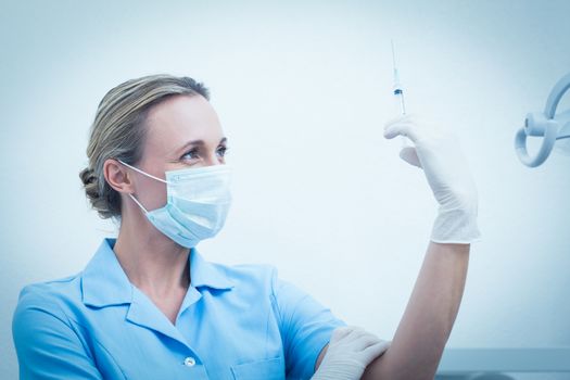 Concentrated female dentist in surgical mask holding injection