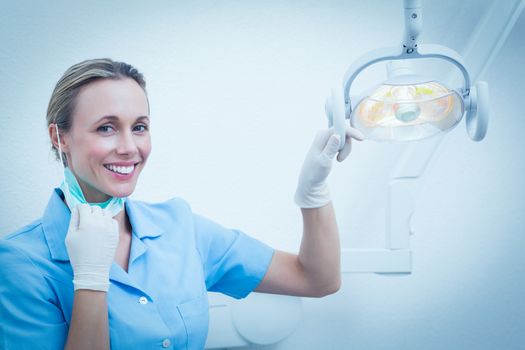 Portrait of smiling female dentist adjusting light