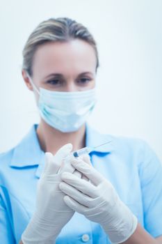 Portrait of young female dentist in surgical mask holding injection