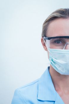Cropped young female dentist wearing surgical mask and safety glasses