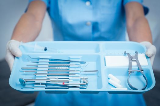 Close up mid section of female dentist holding tray of tools