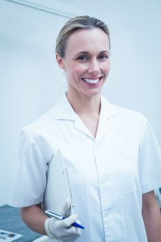 Portrait of smiling young female dentist holding clipboard