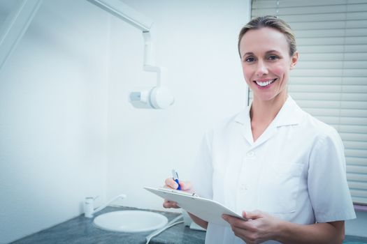 Portrait of smiling young female dentist holding clipboard