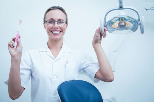 Portrait of smiling young female dentist holding toothbrush