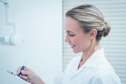 Side view of young female dentist checking reports