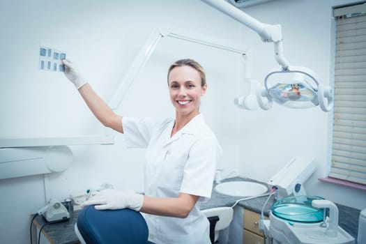 Portrait of smiling young female dentist looking at x-ray