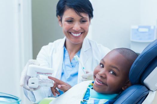 Female dentist showing young boy prosthesis teeth