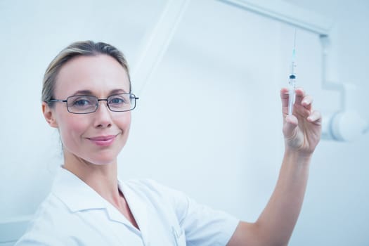 Portrait of smiling young female dentist holding injection