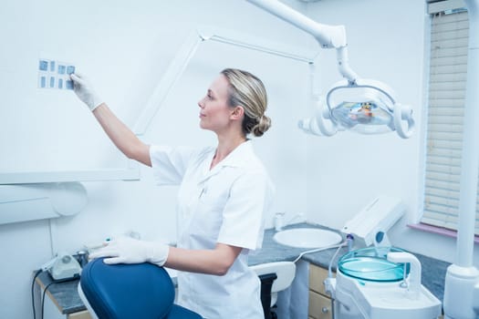 Side view of concentrated female dentist looking at x-ray