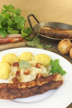 Brawurst with sauerkraut and potatoes on a wooden plate