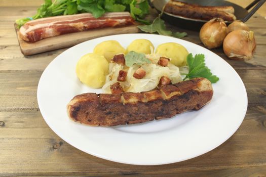 Brawurst and potatoes, sauerkraut with bacon on a wooden plate