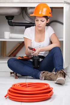 Plumber woman sitting holding a wrench